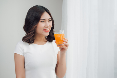 Beautiful asian girl drinking a glass of orange juice.の写真素材
