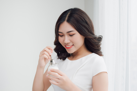 Portrait of young asian woman at home eating yogurtの写真素材