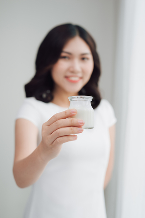 Portrait of young asian woman at home eating yogurtの写真素材