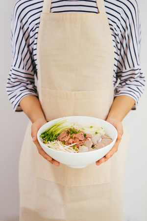 Female chef prepare traditional Vietnamese soup Pho bo with herbs, meat, rice noodlesの写真素材