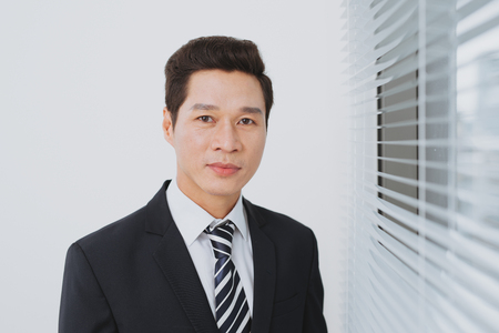 Smiling asian businesman standing by the window.の写真素材