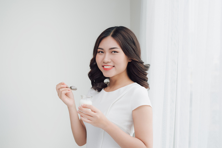Portrait of young asian woman at home eating yogurtの写真素材