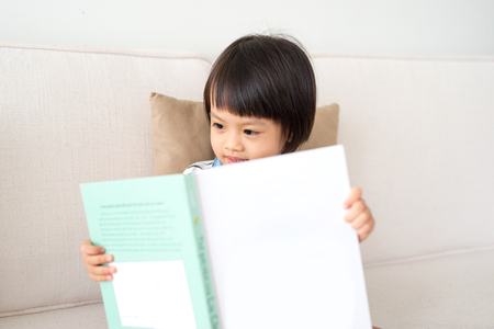 Portrait of happy asian little child girl reading book.の写真素材