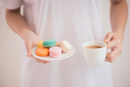 Hands holding colorful pastel cake macarons or macaroonsの写真素材
