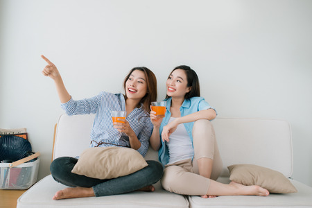 Two girlfriends having a talk on the couch  at homeの写真素材