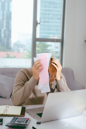 Shocked man holding some documents on sofa livingroomの写真素材