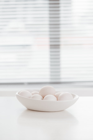 eggs cooked for Easter, in a white bowl on a wooden tableの写真素材