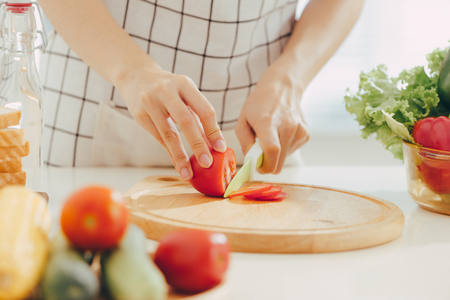 Young woman cutting vegetables in kitchenの写真素材