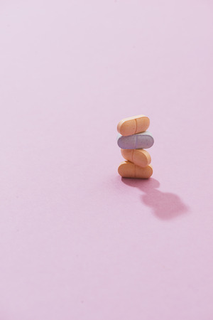 stack of pill and capsule with shadow on pink backgroundの写真素材