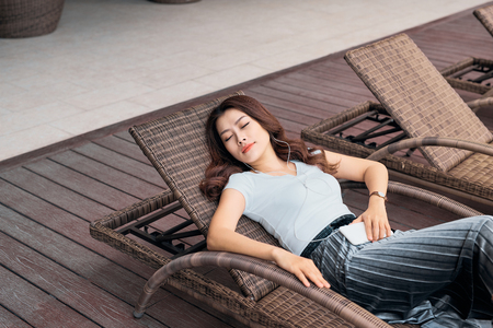 Portrait of pretty cheerful woman resting in vacation on summer season at resort swimming poolの写真素材
