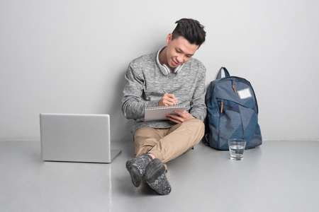 Young man sitting on the floor and using laptop.の写真素材