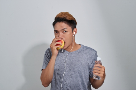 Handsome young muscular sportsman holding a bottle of water and listening to musicの写真素材