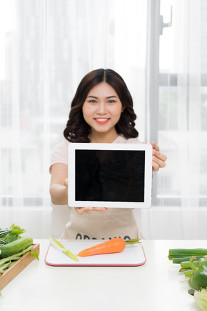 Picture of young asian woman with tablet in kitchenの写真素材