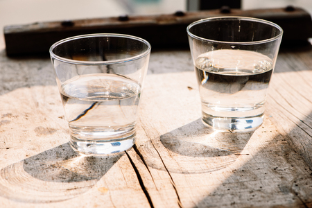 Two glasses of water on table on wooden backgroundの写真素材