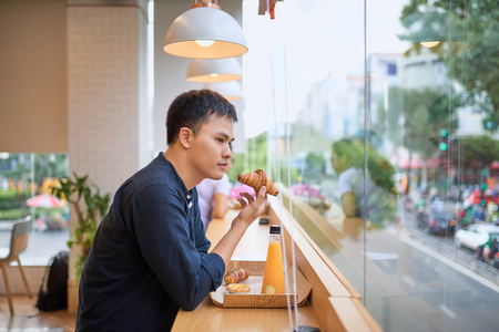 Handsome young freelancer is having a coffee break and dreaming after working at the coffee shopの写真素材