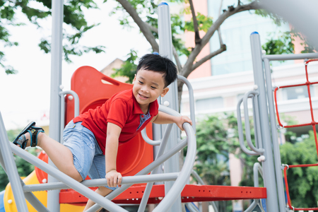 happy little boy climbing on children playgroundの写真素材