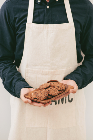 Homemade chocolate cookies on plate in male hands.の写真素材