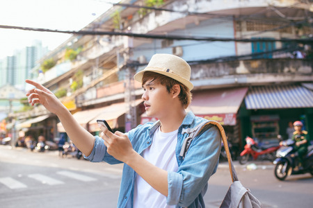Tourism and technology. Concept of online map. Traveling backpacker young man using digital tablet outdoor.の写真素材