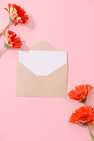Blank greeting card with brown envelope and gerbera flower on pink table with vintage and vignette toneの写真素材