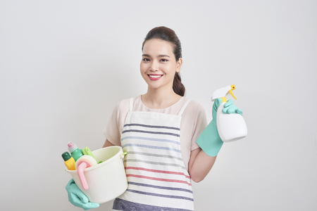 Portrait of happy woman holding in her hands cleaning products while standing at home and starting to clean.の写真素材