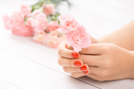 Female hands with red manicure and an open bottle of varnish on the tableの写真素材