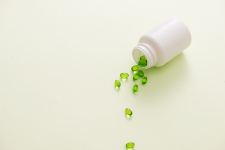 Green capsules in a bottle isolated on white backgroundの写真素材