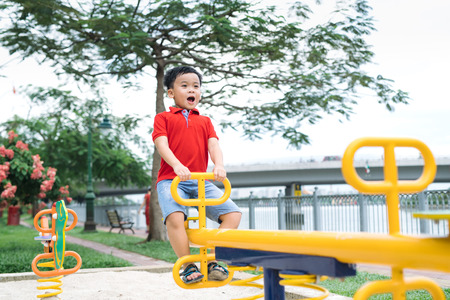 Happy little boy on seesaw outdoorsの写真素材