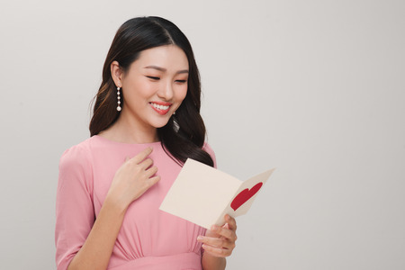 Young beautiful smiling woman holding postcard isolated on white background. St. Valentines Day or International Womens Day conceptの写真素材