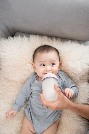 Young mother is feeding her baby at roomの写真素材