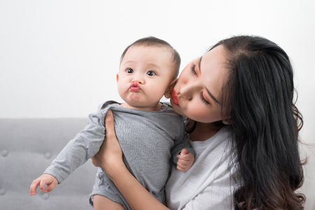 Young mother with her one years old little son dressed in pajamas are relaxing and playing in the living room at the weekend together, lazy morning, warm and cozy scene. Selective focus.の写真素材