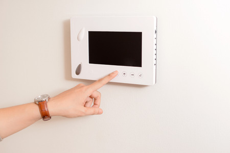 The handsome man opening door of the apartment using video door phone of intercom system.