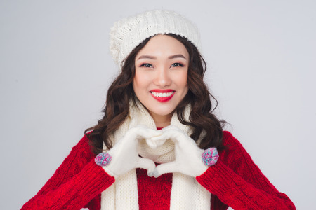 Beautiful smiling fashion model face with red lips in warm clothing gesture heart shapeの写真素材