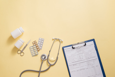 Stethoscope and Medical History Report Isolated on yellow desktopの写真素材