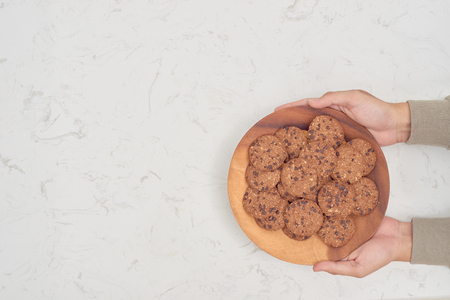 Plate of cookies in male hands on dark old wooden background top viewの写真素材