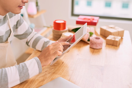 Joyful pleasant male seller working with digital tablet in a gift shop.の写真素材