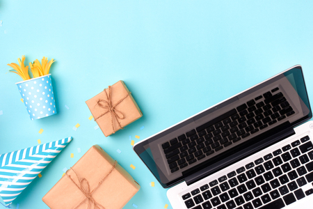 Gift box, birthday party things and laptop on a blue backgroundの写真素材