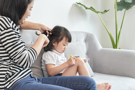 mother braiding hair of her daughterの写真素材