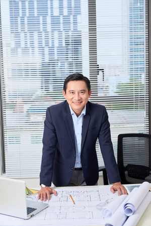 Asian businessman, an engineer with the work plan, standing in the office.の写真素材