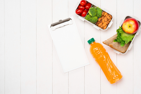 Healthy lunch boxes with sandwich, fresh vegetables, fruits and nuts on white wooden background. From top viewの写真素材