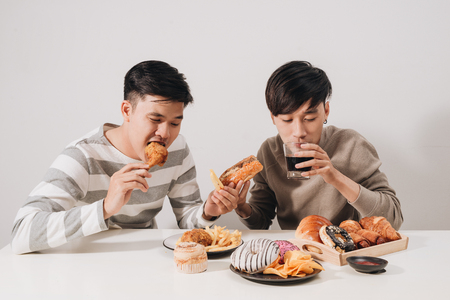 Two friends eating burgers. french fries, having fun and smilingの写真素材