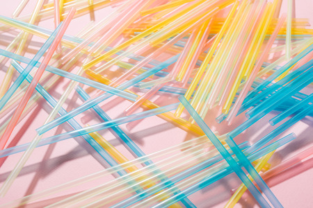 Colorful plastic straws on pink background. Event and party supplies. Earth pollution conceptの写真素材