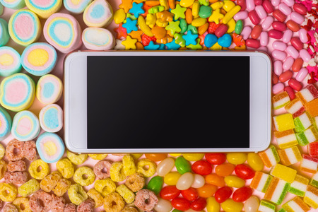 `Marshmallows, candies with smartphone, on pastel background, decoration for love and valentine day concept.の写真素材