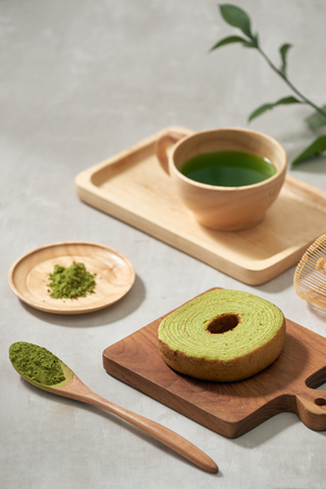 Green tea matcha in a wooden cup with German cake on the brown mat close-upの写真素材