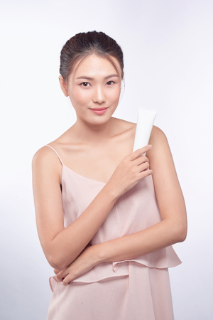 Beautiful asian woman. Beauty female face with perfect make up. Holding cream for body and faceの写真素材