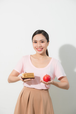 The girl in one hand has an apple, in the other hand a cake.の写真素材