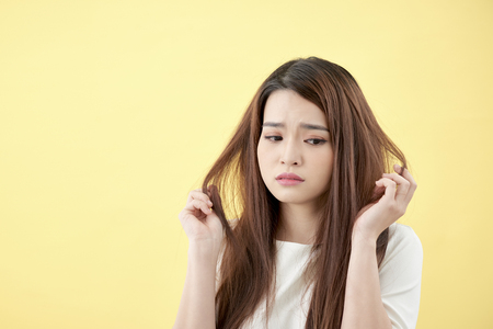 Young asian woman brushing her hair and disappointing condition her hairの写真素材