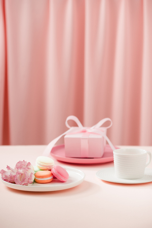 Happy woman/mother"s Day image of a coffee or tea cup and lisianthus flower with macaroon and gifts beside on drapes of pink.の写真素材