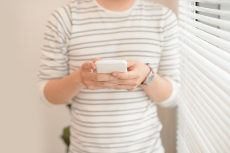 Happy young man using his smart phone at officeの写真素材