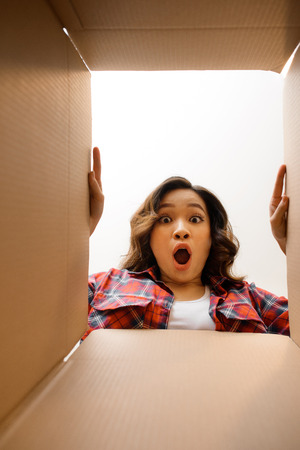 Smiling young woman opening a carton box, relocation and unpacking conceptの写真素材
