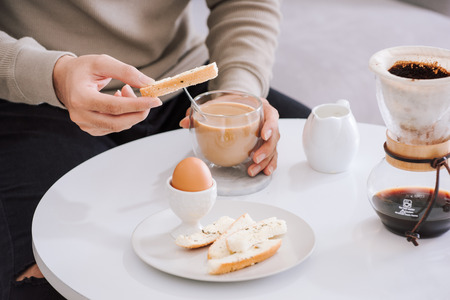 Fresh delicious breakfast with soft boiled egg, crispy toasts and cup coffee in living roomの写真素材